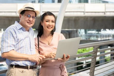 Couple Using Laptop While Standing On Bridge In City Stock Photos