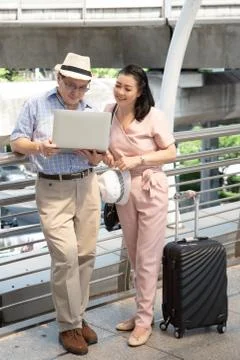 Couple Using Laptop While Standing On Bridge In City Stock Photos