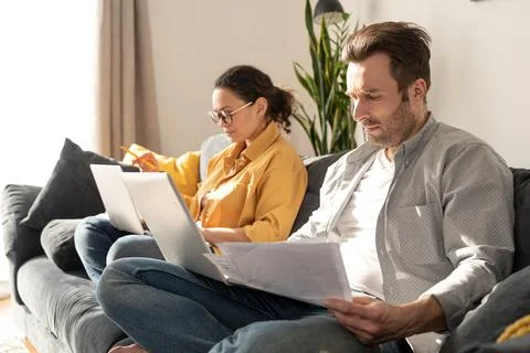 Couple using laptops for remote work on the sofa at home Foto stock