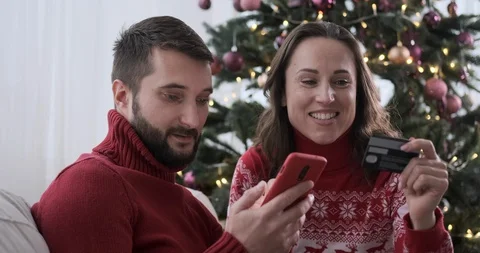 Couple using mobile phone and credit card for Christmas shopping Stock Footage 129425234