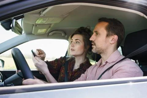 Couple using mobile phone for checking direction while sitting in car Stock Photos