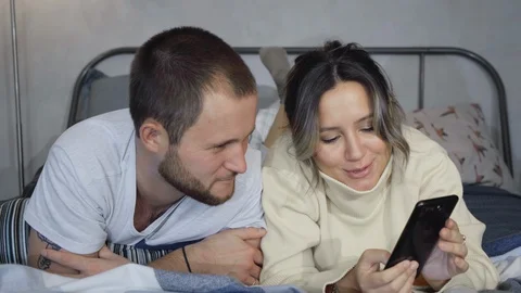 Couple using mobile phone to live stream, video call to friends in bed Stock Footage 128546334