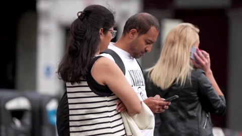 A couple using a mobile phone, with people walking past in the street Video stock 279548309