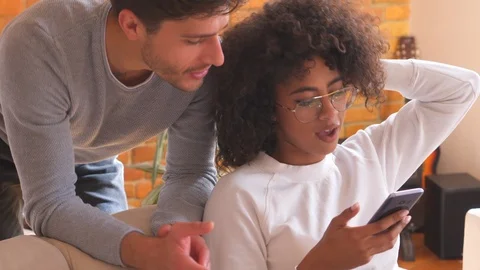 Couple using mobile phone on sofa at home Stock Footage 98335157