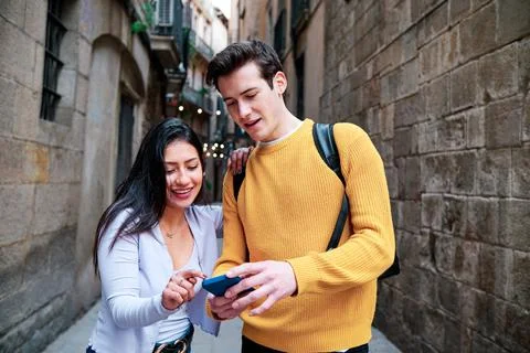 Couple using a mobile phone while walking outdoors. Stock Photos