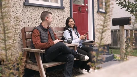 Couple using phone on bench at front porch Vídeo Stock 221039420