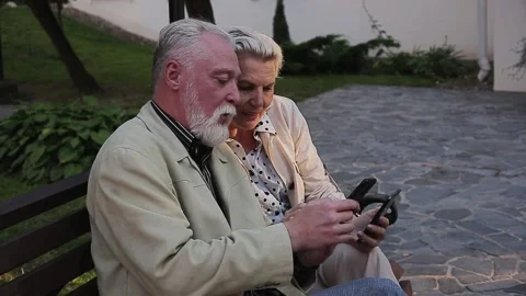 Couple using sharing smart phone while sitting on bench Stock Footage 168911149