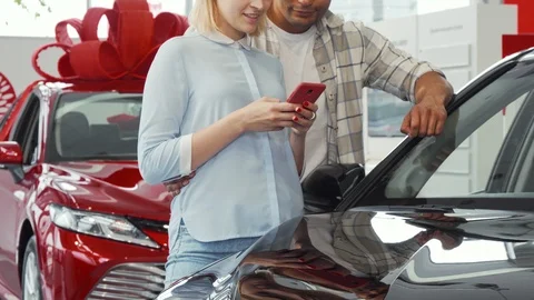 Couple using smart phone while buying a new car Stock Footage