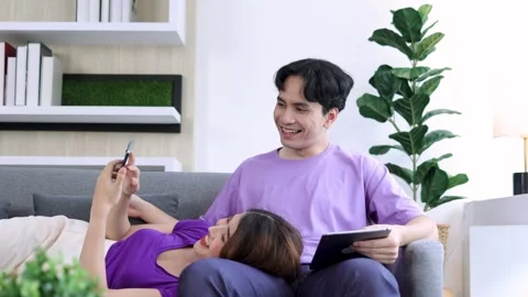 Couple using smartphone and tablet on the sofa at home Stock Footage 245246752