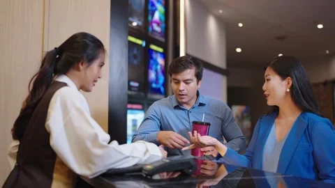 A couple using smartphone scan paying, buying movie ticket in cinema box office. Video stock 248764747