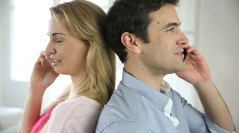 Couple using smartphone, sitting back to back Stock Footage 37620207