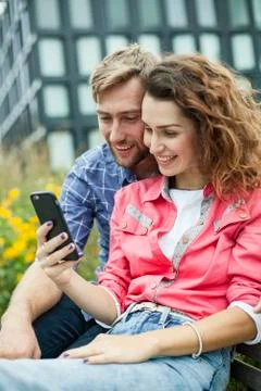 Couple using smartphone together outdoors Stock Photos