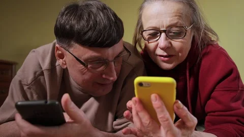 Couple using smartphones while lying on bed at home in the evening Video stock 309948447