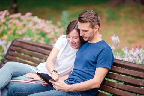 Couple using tablet and cellphone in public park. Stock Photos