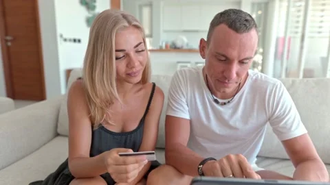 Couple using a tablet and sitting on the couch Stock Footage 132990891