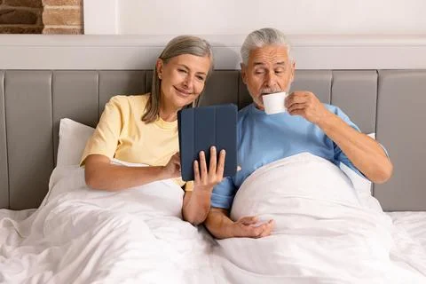 Couple Using Tablet On Bed For Digital Research And Technology Stock Photos