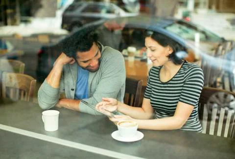 Couple using tablet computer in cafe seen through glass window Foto stock