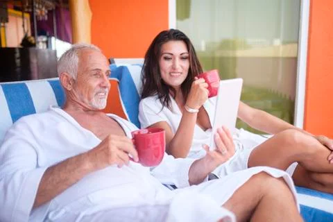 Couple using tablet on loungers Stock Photos