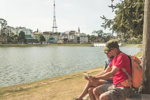 Couple using tablet smart phone in green city park lake at Da Lat town, Vietn Stock-Fotos