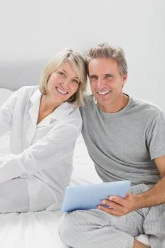 Couple using their tablet pc smiling at camera 스톡 사진