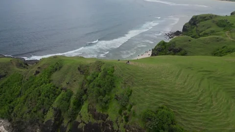Couple Ventures Down Lush Slope To Peaceful Oceanfront With Rocks And Waves 스톡 동영상 330371916