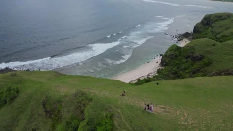 Couple Ventures Down Lush Slope To Peaceful Oceanfront With Rocks And Waves 스톡 동영상 330372031