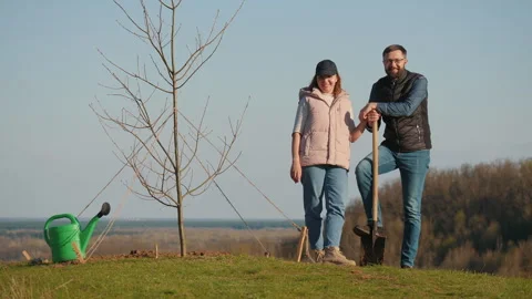 Couple of volunteers discussing something while standing next to a planted tree Stock Footage 277876561