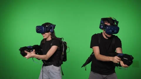 A couple in a VR headset is playing a virtual game on a green background. Stock Footage 316592466