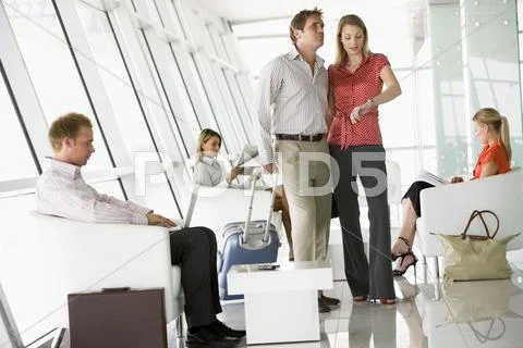 Couple waiting with other airline passengers in departure gate Stock Photos