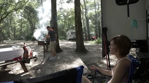Couple Waits for Food to Finish Grilling While Camping Stock Footage