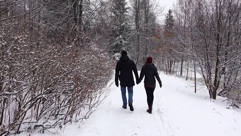 Couple walk along snow path, hold hands, nice winter park, POV follow Stock Footage 70018873