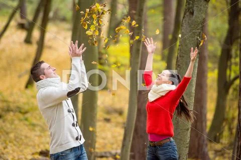 Couple on a walk in autumn park throwing leaves Stock Photos