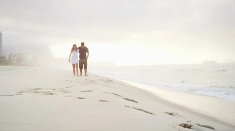 Couple walk down a beach holding hands Stock Footage 49547610