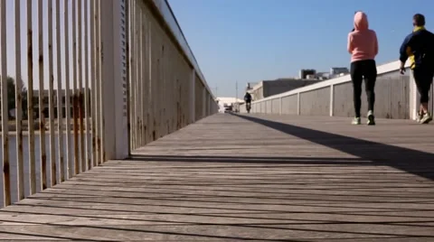 A couple walk over a bridge, a guy is cycling in the distance Stockbeeldmateriaal 46209346