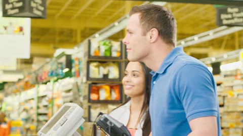 Couple walk through check out counter and exchange smiles with the cashier Stock Footage 34003591