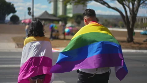 Couple walk under rainbow flag cape. Gay lesbian lgbt symbol. Lgbtq parade. Stock Footage 303501566