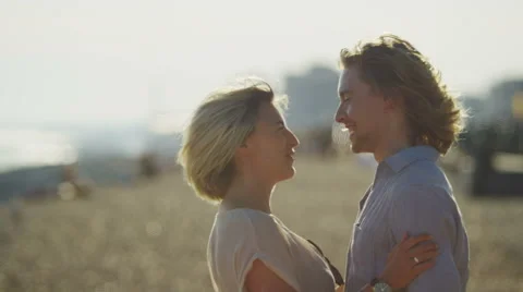 Couple walking along the beach stop and share a kiss Stock Footage 52154935