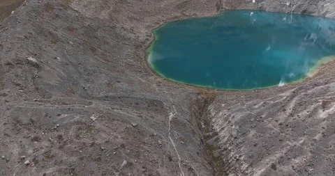Couple walking along a path next to a lake surrounded by cliffs Video stock 250841774