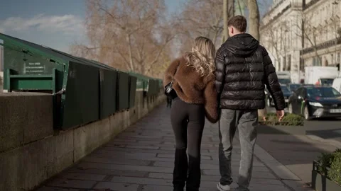 Couple walking along Seine River in Paris France Man points to the distance Back Stock Footage 328569282