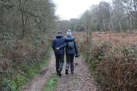 A couple is walking arm in arm down a path in the woods Stock Photos