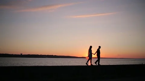 Couple is walking on the bank of the river at sunset Stock Footage 68355853