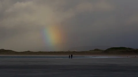 Couple walking on beach with a big rainbow Stock Footage 102799185