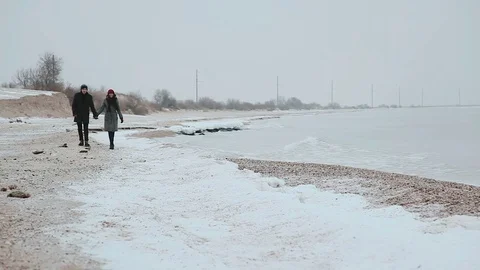 Couple walking on beach holding hands, smiling, talking Stock Footage 70994115