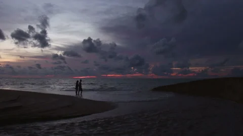 A couple walking on beach at sunset . Stock Footage