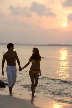 Couple walking on beach in sunset Stock Photos