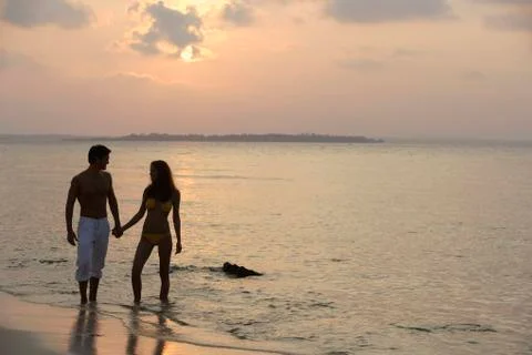 Couple walking on beach in sunset Stock Photos