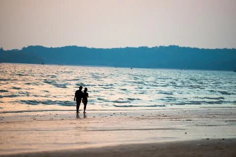 Couple walking on beach at sunset Stock Photos