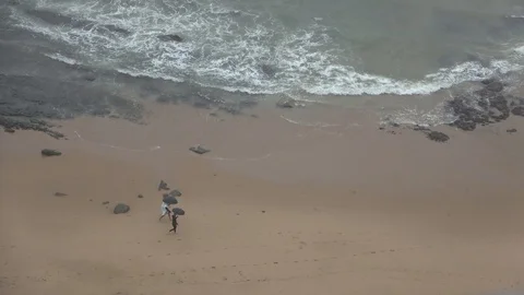 Couple walking on beach with umbrellas while its raining outside Video stock 121973551