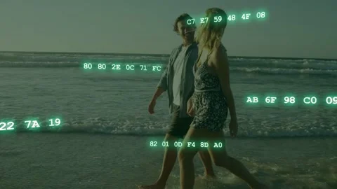 Couple walking on beach wading into surf and activating green hex code overlays Stock Footage 333704660