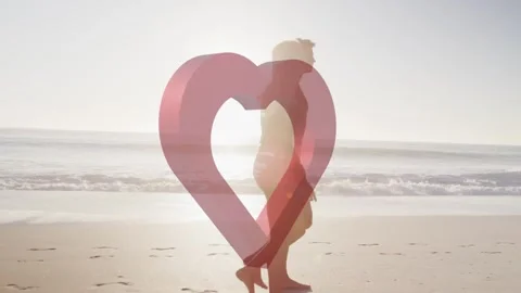 Couple walking on beach while pulsing red heart overlay shifting over torsos, Stock Footage 333790320
